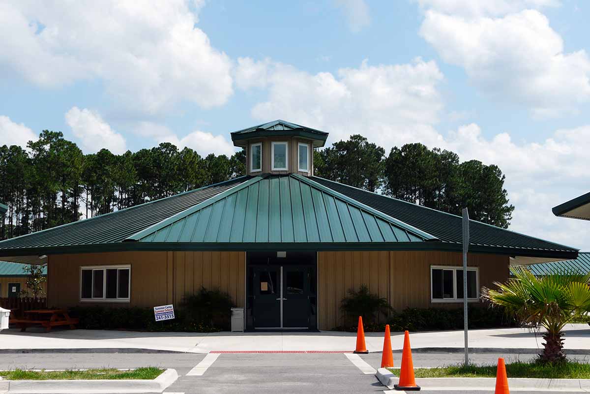 Florida's Foundation Academy is a tan, octagon-shaped metal building with a cupola atop a green standing seam roof. 